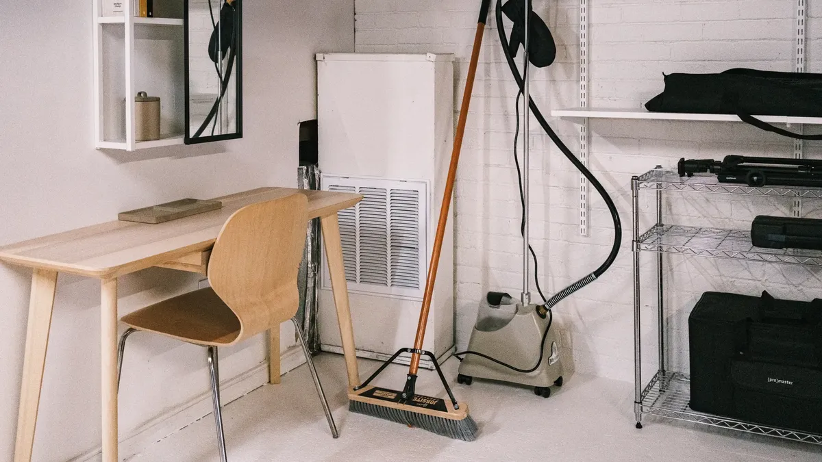 정리된 사무실 공간에 wooden desk, chair, broom, 및 청소 장비가 있습니다.