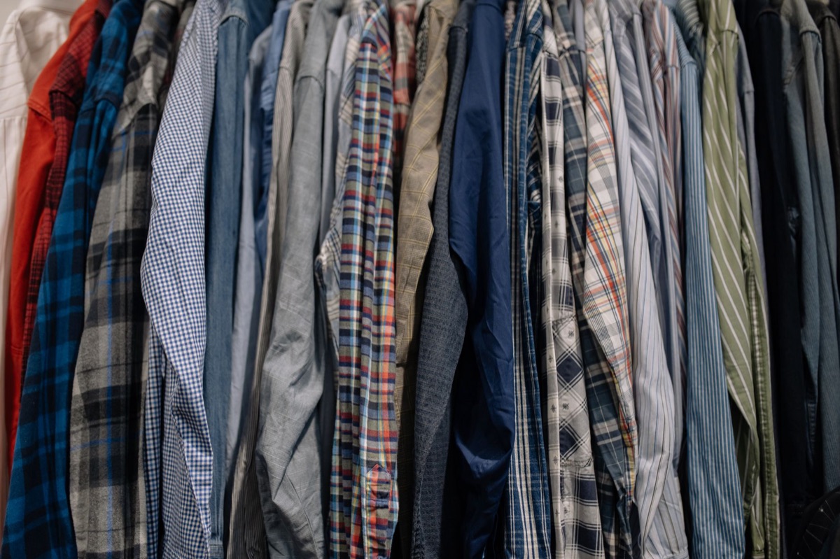 A well-organized closet with clothes hanging on wooden hangers with consistent spacing.