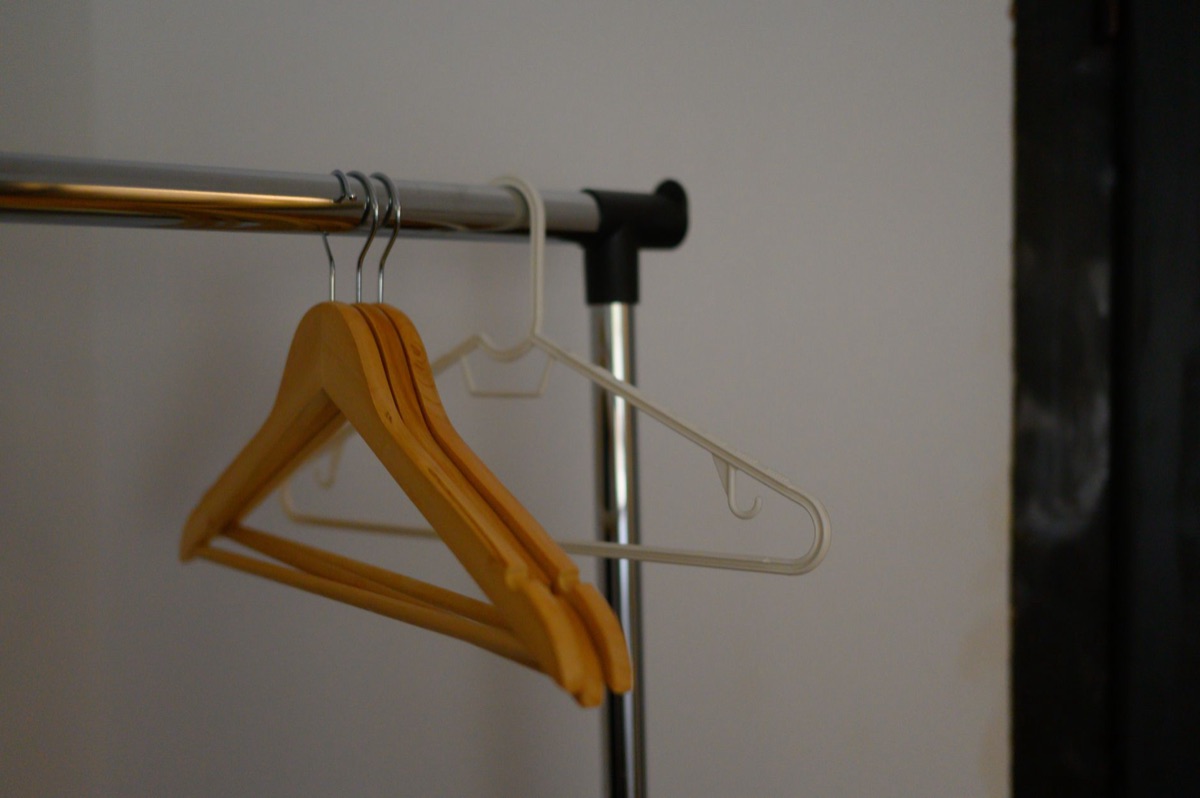Netjes opgehangen kleding aan houten hangers in een kast.