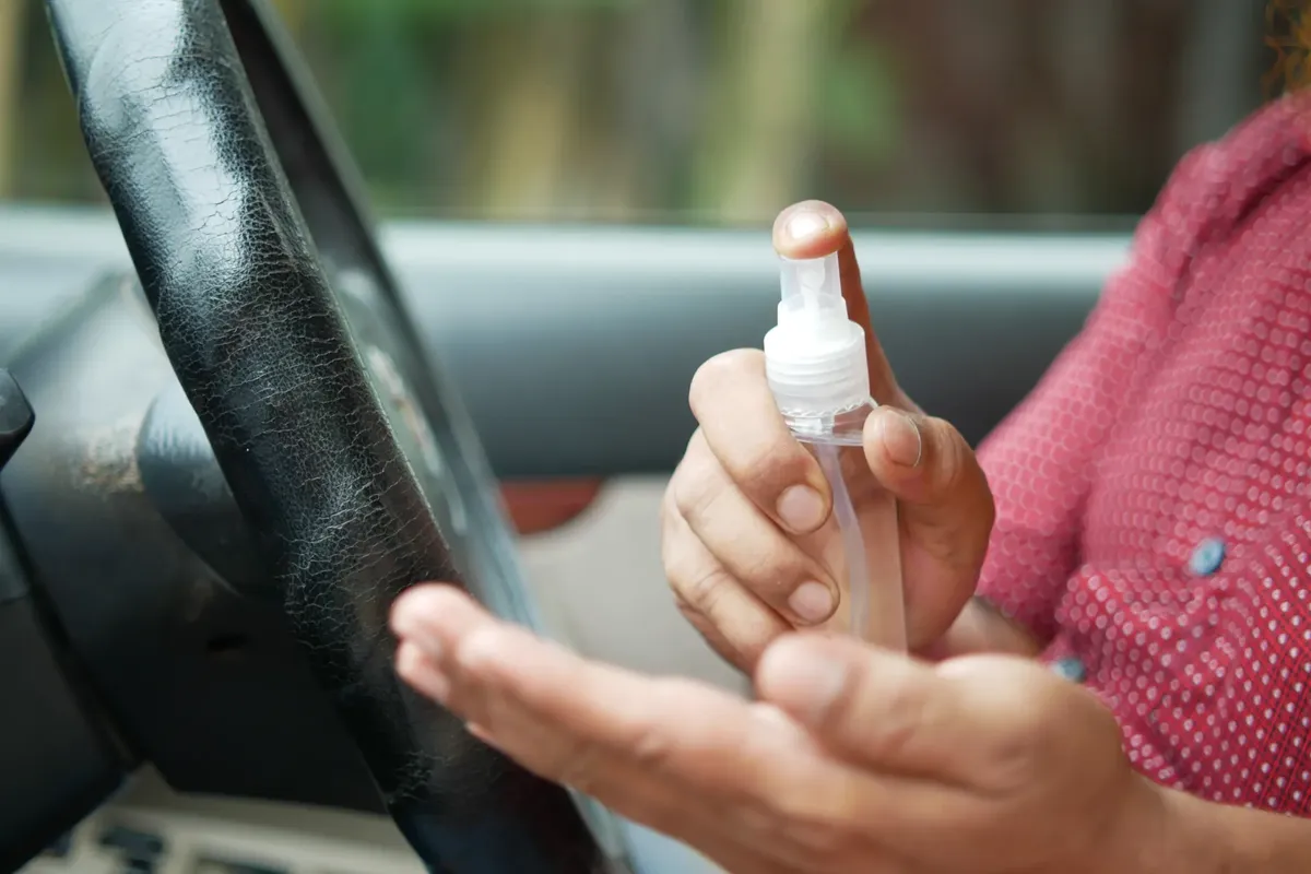Close-up of a person sanitizing hands in a car for hygiene.