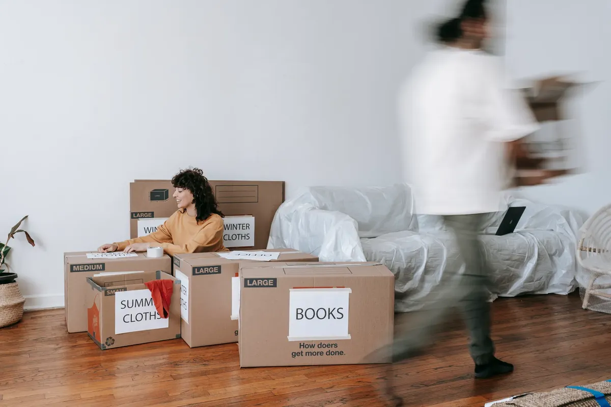 A couple packing labeled boxes in a minimalist living room, preparing for moving day.
