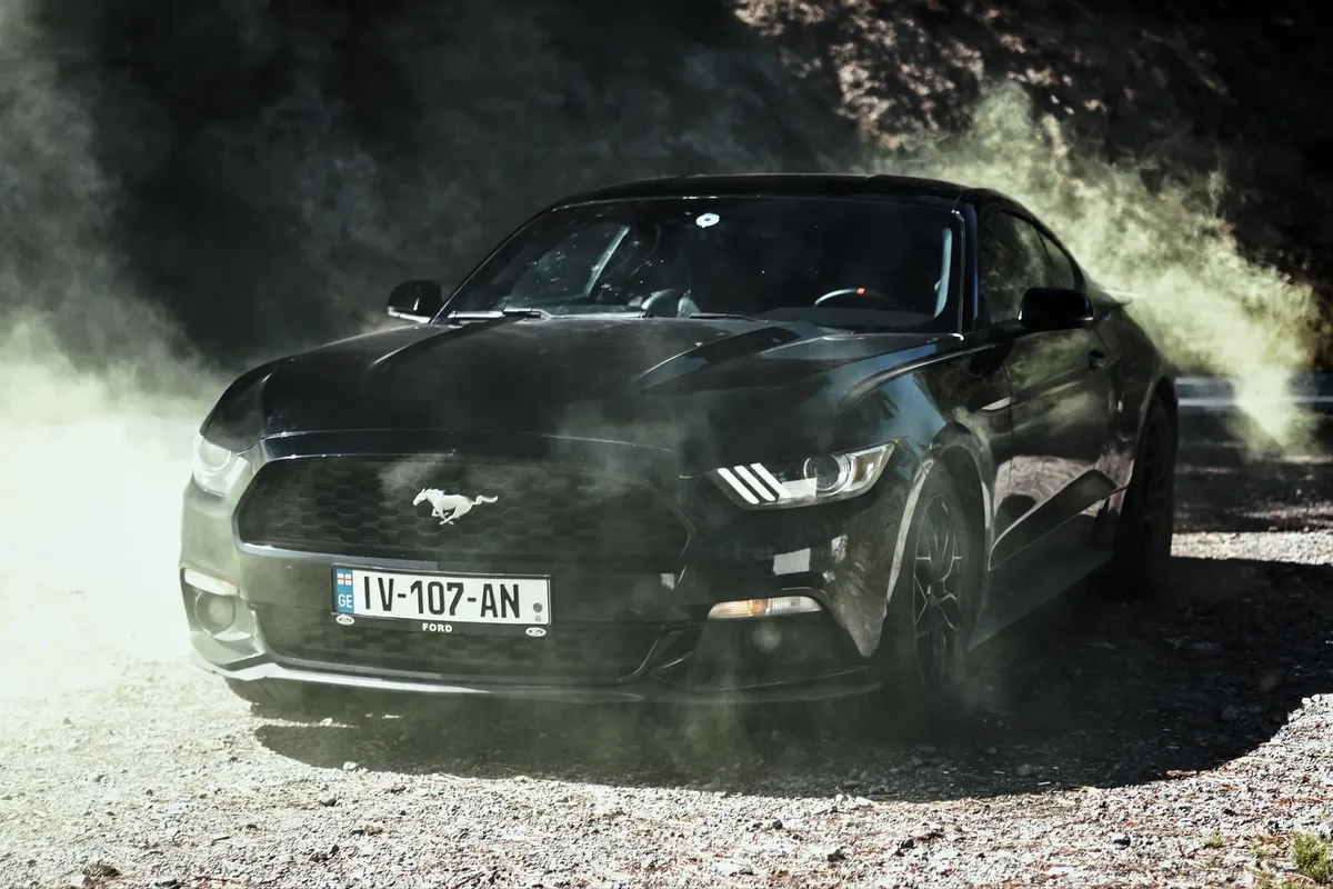 A sleek black sports car engulfed in dust, emphasizing power and dynamic movement.