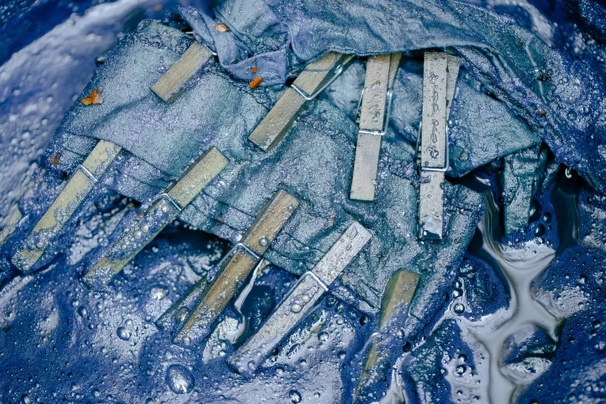 細部特寫的潮濕衣夾附著於藍色布料上，強調紋理